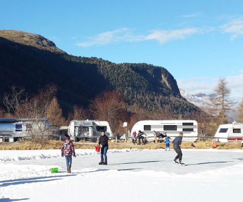 Campingplatz Morteratsch im Winter mit zugefrorenem See und Menschen auf Schlittschuhen