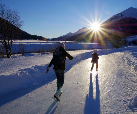 Donna e bambino piccolo pattinano sul sentiero del ghiaccio di Madulain 