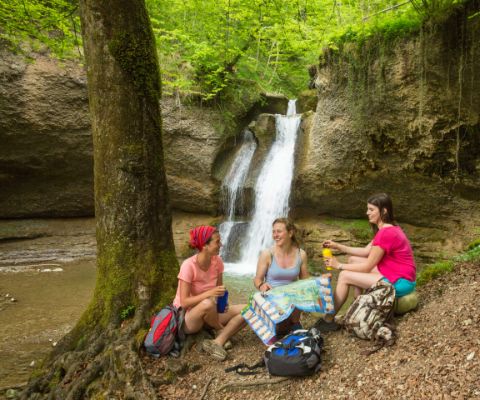 Drei Frauen picknicken vor einem Wasserfall