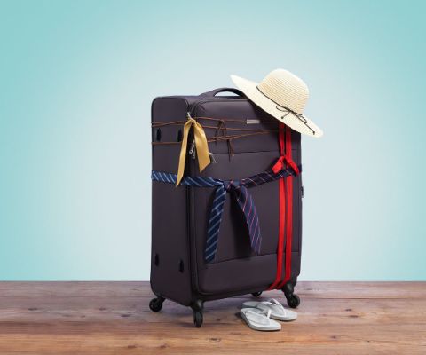 Gepackter Koffer mit Sonnenhut und Bändern