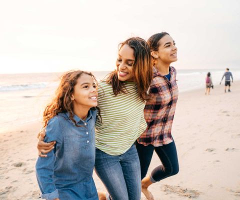 Vacances avec des adolescentes: une mère marche sur la plage avec ses deux filles. 