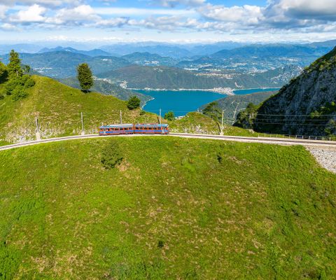 Le train à crémaillère sur le Monte Generoso devant un panorama alpin et le lac de Lugano