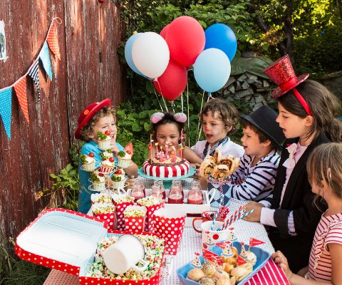 Bambini che ammirano una torta a forma di circo con candeline accese sul buffet