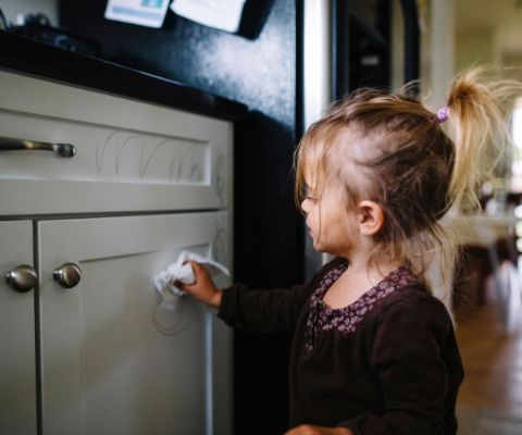 Una bambina toglie strisce colorate dall’armadietto della cucina