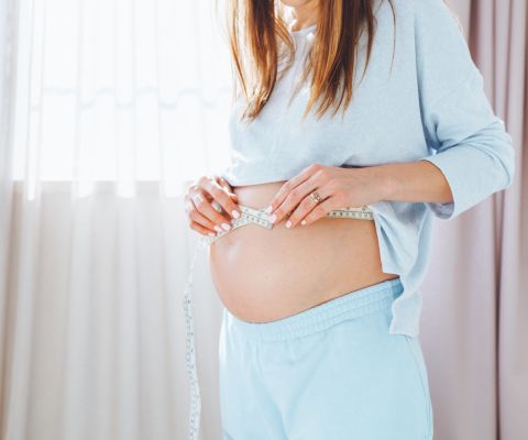 Una donna incinta si misura la pancia con un metro