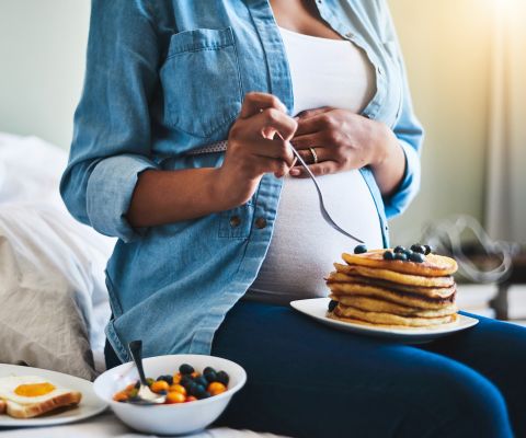 Schwangere isst mit Genuss Pancakes