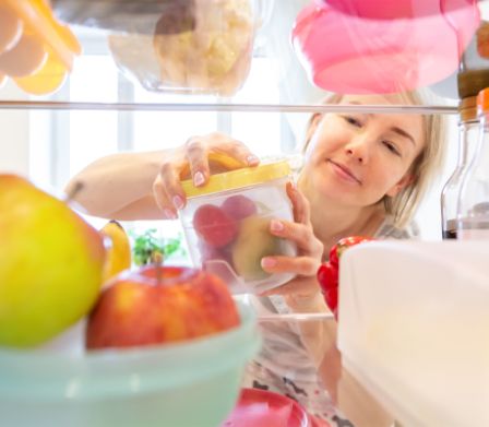 Eine Frau räumt Frischhaltedosen in den Kühlschrank