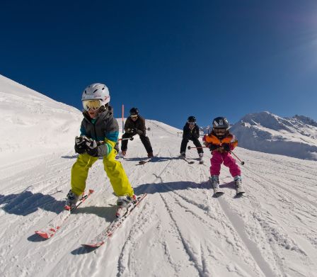 Quattro bambini che sciano in una bellissima giornata di sole