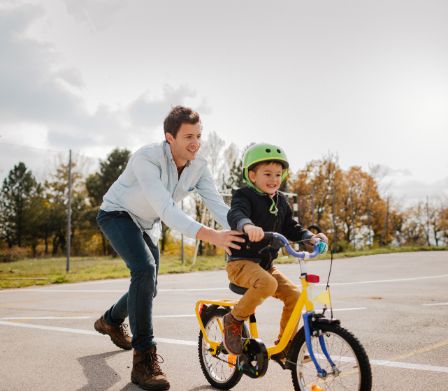 Un padre insegna al figlio ad andare in bicicletta