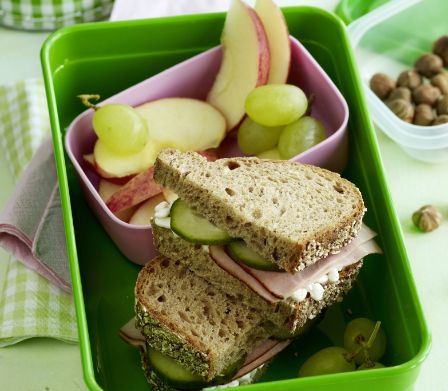Boîte à collation avec sandwich de pain complet au jambon, fruits et noisettes