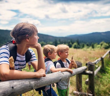 Tre bambini guardano in lontananza in un campo 