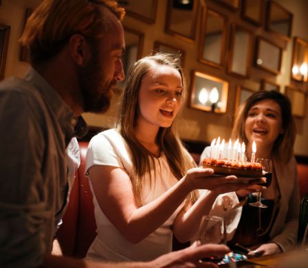 Ragazzina mentre soffia sulle candeline della torta di compleanno
