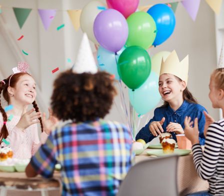 Bambini festeggiano un compleanno con palloncini e cupcake
