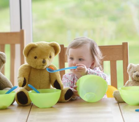 Una bimba piccola dà da mangiare ai suoi orsetti
