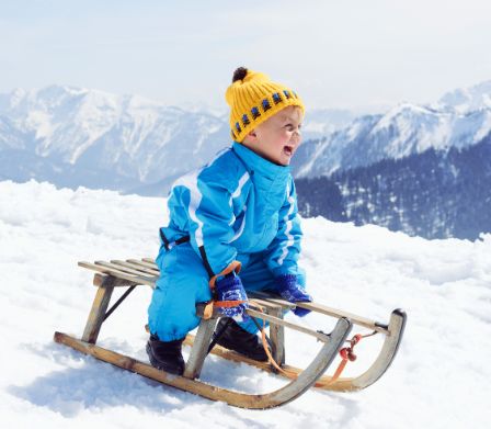 Kleines Kind auf einem Schlitten im Schnee