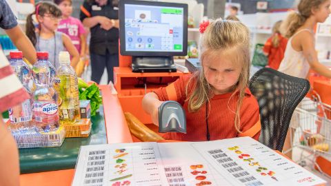 Mädchen scannt Artikel an der Kasse der Mini-Migros Mädchen scannt Artikel an der Kasse der Mini-Migros