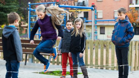 Cinque bambini giocano con l’elastico per saltare