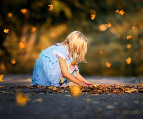 Bambina gioca con foglie autunnali