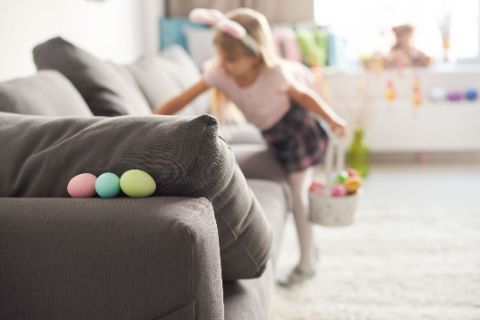 Ein Mädchen sucht an Ostern versteckte Eier im Wohnzimmer