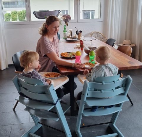 Eine Mutter füttert ihre Zwillinge mit Babynahrung am Esstisch