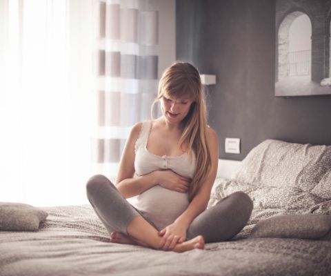 Femme enceinte assise sur un lit