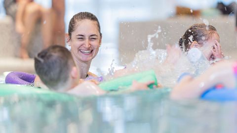 Eine Frau spielt mit ihren Kindern im Wasser.