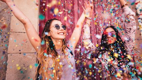 Zwei junge Frauen feiern und werfen ausgelassen mit Konfetti 