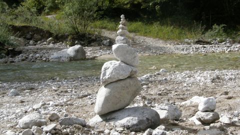 Steine zu einem Turm aufgeschichtet vor einem Bachlauf