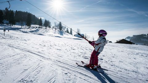 Ein Kind auf Skiern nutzt den Schlepplift des verschneiten Skigebietes Atzmännig bei Goldingen