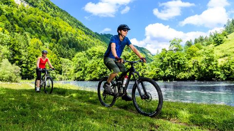 Una coppia sportiva va in bicicletta lungo il fiume nel Giura