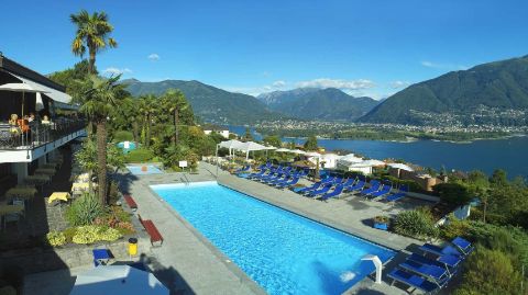 Vue sur une piscine d’hôtel avec un lac et les montagnes en arrière-plan Vue sur une piscine d’hôtel avec un lac et les montagnes en arrière-plan