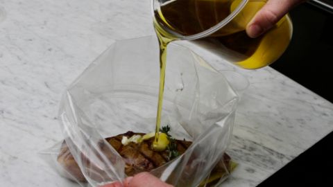 Homme en train d’ajouter de l’huile dans un sac en plastique contenant un morceau de viande et des épices