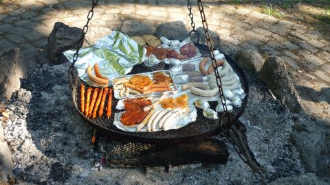 Verschiedenes Grillgut auf Alufolie auf einem grossen Hängegrill Verschiedenes Grillgut auf Alufolie auf einem grossen Hängegrill