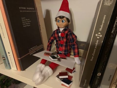 Weihnachtswichtel macht Unordnung im Bücherregal