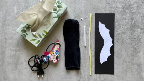 Le matériel pour fabriquer une chauve-souris avec une chaussette noire.