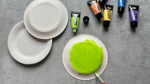 Pitturare i piatti di carta con colori diversi.