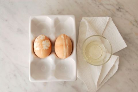 Gefärbte Eier in Behälter und Haushaltpapier mit Öl in Schälchen