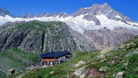 SAC Hütte vor schneebedecktem Alpenpanorama