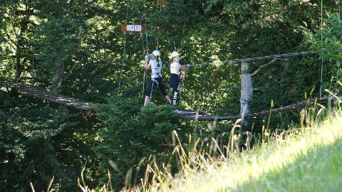 Dei bambini agganciati a dispositivi di sicurezza attraversano un vacillante ponte sospeso al Parco avventura di Rigi Dei bambini agganciati a dispositivi di sicurezza attraversano un vacillante ponte sospeso al Parco avventura di Rigi