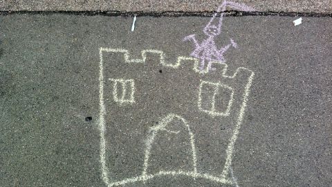 Un dessin d’enfant représentant un château et une gente demoiselle sur l’asphalte Un dessin d’enfant représentant un château et une gente demoiselle sur l’asphalte