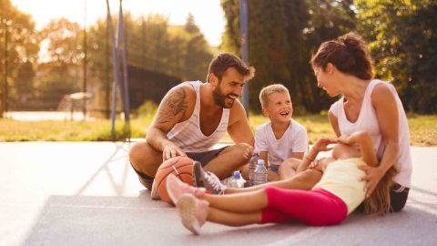 Eine Familie sitzt lachend auf dem Sportplatz
