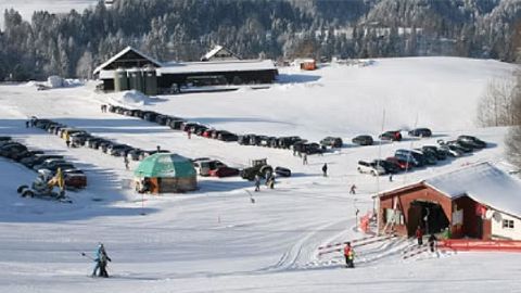 Ansicht des verschneiten Skigebietes Fischenthal-Aurüti mit Liftanlage und Parkplatz