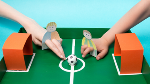 Kinder spielen Fingerfussball auf einem selbst gebastelten Feld