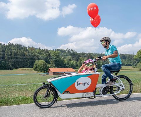 Vater fährt Famigros Cargo-Bike mit Kindern 