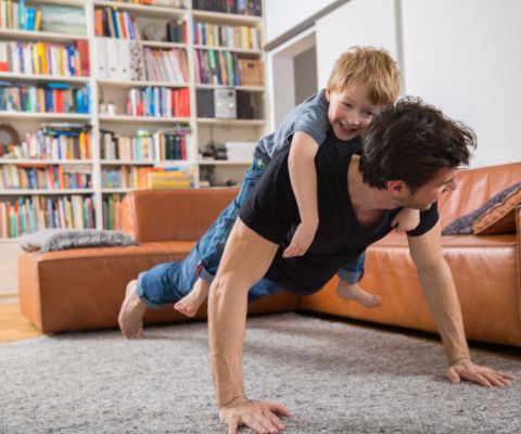 Un père s’entraîne avec son fils dans la salle de séjour