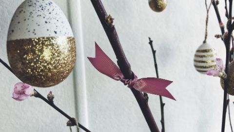 Branche avec œufs dorés et ruban de satin rose