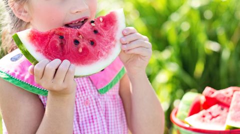 Une fille mange un morceau de pastèque Une fille mange un morceau de pastèque