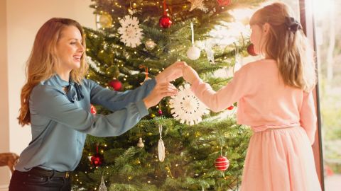 Madre e figlia in abiti festivi che decorano l’albero