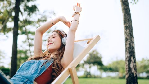 Une jeune femme portant des écouteurs se détend sur une chaise longue 