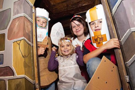 Des enfants déguisés en chevaliers et princesses regardent par une porte